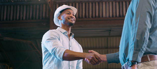 Businessman in hard hat shaking hands.