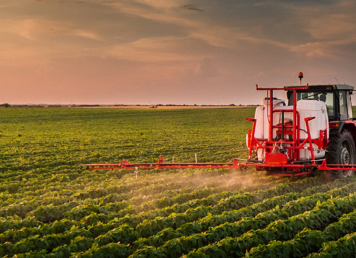 Tractor spraying crops with a pull sprayer.