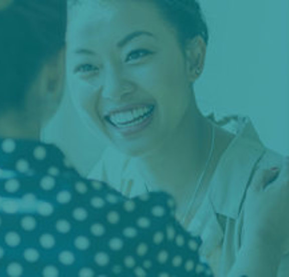 Businesswoman looking forward, smiling at another woman.